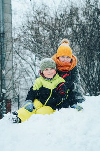 Girl with brother in snow during winter