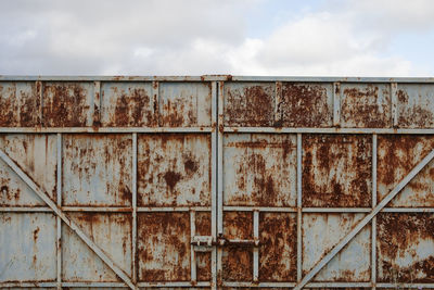 Rusty metal fence against sky