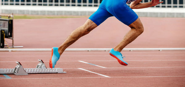 Low section of man running on track in stadium