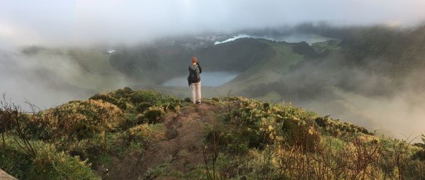 Rear view of man standing on mountain against sky