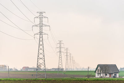 Electricity pylon on field against sky