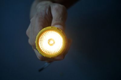 Close-up of hand holding torch against black background