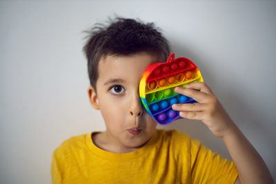 Boy in a yellow t-shirt plays a fashion game pop it in the form of a silicone apple