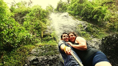 Low angle view of couple standing against waterfall