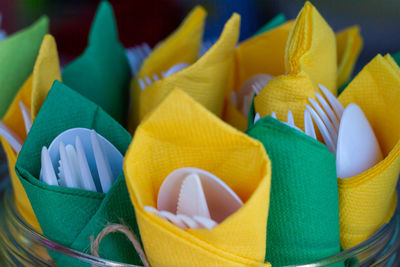 Pack of plastic fork and spoon cover with yellow and green tissue paper,in summer party 2021.italy.