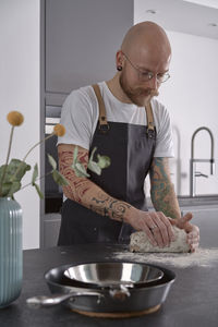 Man kneading rye sourdough on floured surface