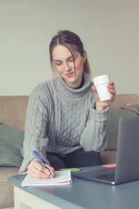Young woman using mobile phone while sitting on table