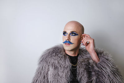 Thoughtful man with make up looking away against white background