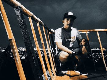 Full length portrait of young man standing on railing