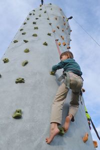 Low angle view of boy climbing on wall