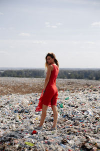 Portrait of young woman standing on land against sky