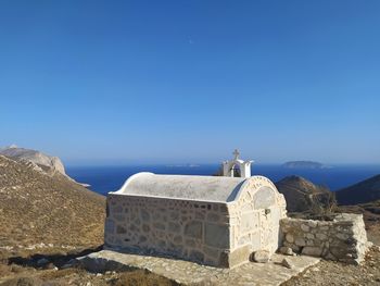 Greek chappelle up in the mountains against clear blue sky and sea view