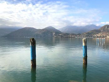 Wooden posts in lake against sky