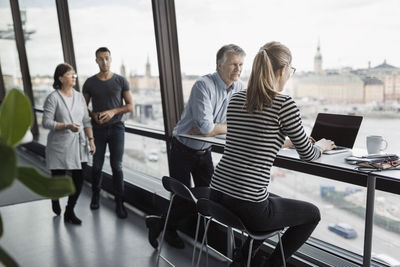 Business people discussing by window in office