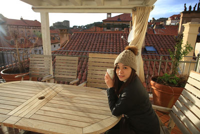 Portrait of young woman holding cup while sitting at outdoor cafe