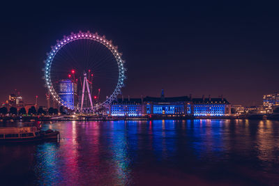 Illuminated ferris wheel in city at night