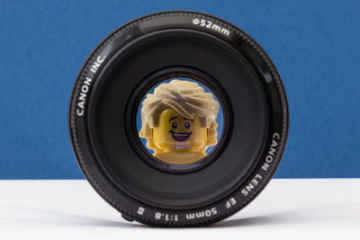 Close-up of camera lens and toy on table against blue wall