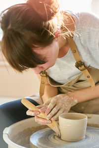 Young woman making pot at workshop