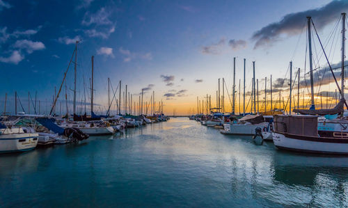 Boats moored at harbor against sky during sunset