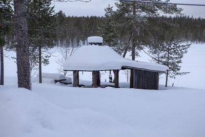 Built structure on snow covered field by trees