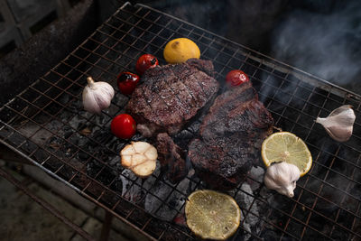 Garlic,tomatoes and meat on the grill on hot coals with smoke.