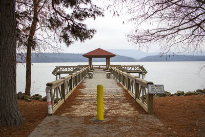 Pier on beach against sky during sunset