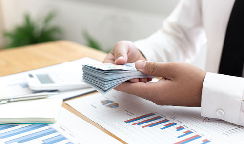 Midsection of man holding banknotes on table