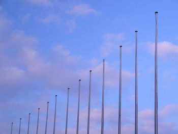 Low angle view of flag poles in a row against clear sky