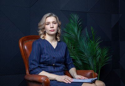 Portrait of a successful female psychologist in her office, notebook in hand, in her chair.