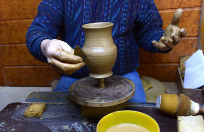 Craftsperson shaping pot on pottery wheel