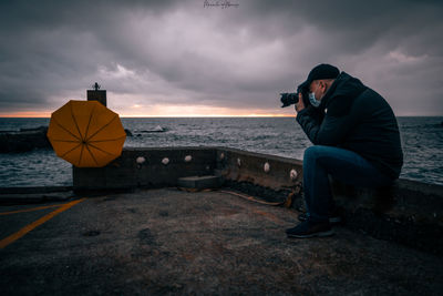 Man photographing sea against sky