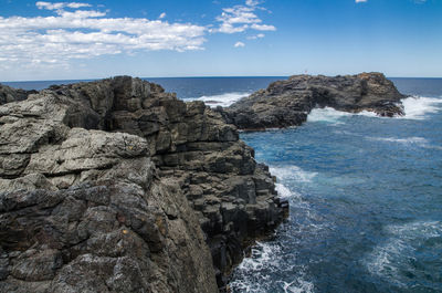 Rock formations by sea against blue sky