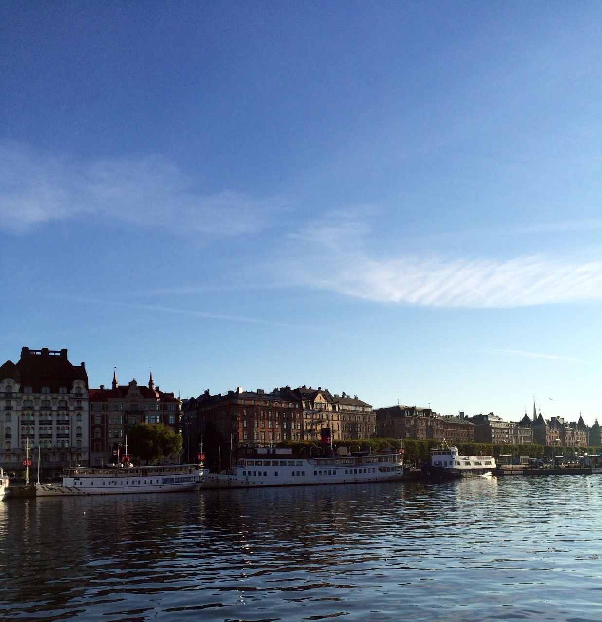 water, building exterior, architecture, built structure, waterfront, sky, blue, river, sea, city, rippled, residential building, residential structure, house, day, incidental people, outdoors, nature, cloud, nautical vessel