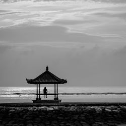 Woman sitting at beach against sky