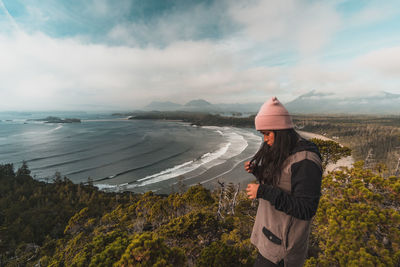 Woman standing by trees and sea against sky