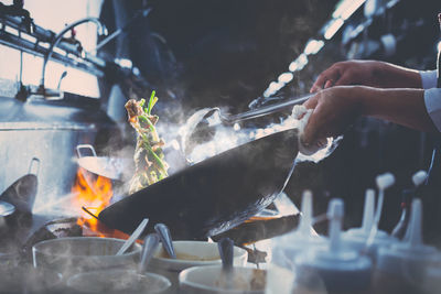 Midsection of person preparing food on barbecue grill