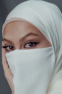 Close-up portrait of veiled muslim woman with white hijab from high angle.