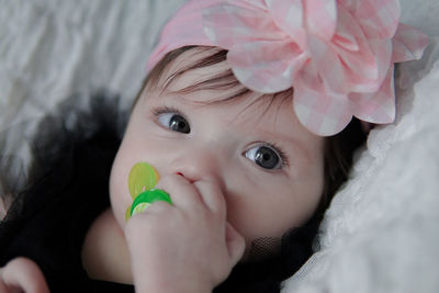 Close-up portrait of cute baby girl lying on bed