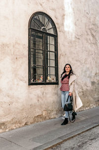 Beautiful young woman walking on sidewalk by old building. lifestyle, city, casual, stylish 