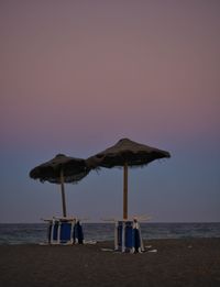 Close-up of thatched roof at beach against clear sky during sunset