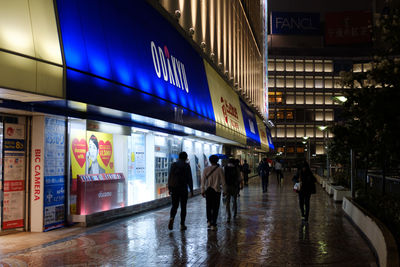 People walking on illuminated city at night