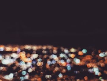 Defocused image of illuminated city against sky at night