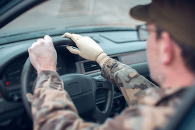 Man with prosthetic arm driving car