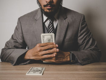 Midsection of businessman with paper currency at table