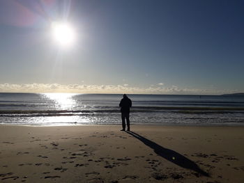 Silhouette man walking on beach against sky during sunset