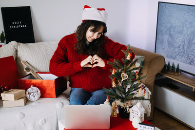 Portrait of woman using phone while sitting on sofa at home