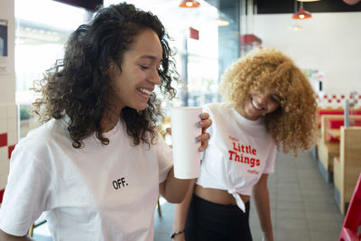 Delighted young african american female best friends drinking coffee in cafe and enjoying weekend together