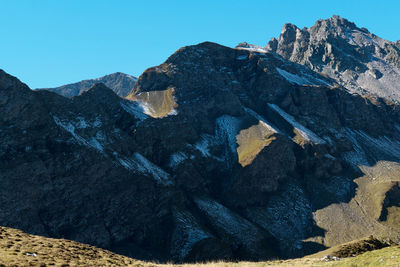 Rock formations by mountains against clear sky