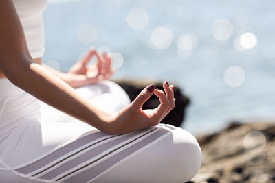 Midsection of woman meditating at beach