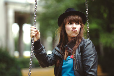 Portrait of happy young woman holding swing in playground